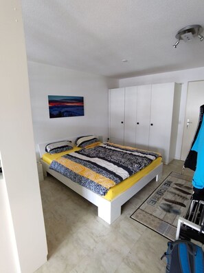 Ein Schlafzimmer mit Bett, Kleiderschrank und einem Bild an der Wand.