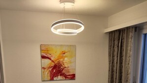 A dining area with a table, chairs, a modern pendant light, and a large abstract painting on the wall. - Valère C 222 # 2-bed apartment, Dusche, WC 2-Bettwohnung, Dusche, WC by Interhome (Leukerbad)