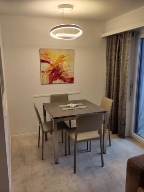 A dining area with a table, chairs, a modern pendant light, and a large abstract painting on the wall.