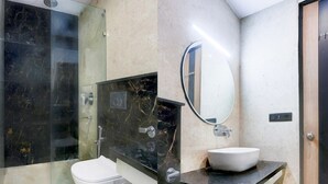 A modern bathroom with a glass shower enclosure, a white toilet, a black marble vanity, and a large mirror. - Premium Townhouse Majra Isbt Dehradun (Dehradun)