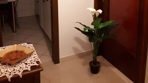 A hallway with a potted plant, a framed picture on the wall, and a wooden door.