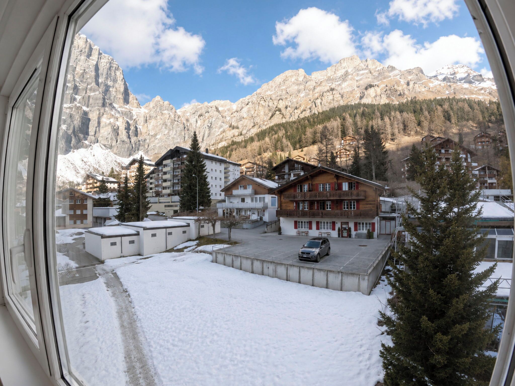 A view of a hotel with multiple buildings, a parking area, and snow-covered ground.