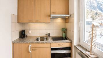 A compact kitchen with wooden cabinets, a stainless steel sink, and an oven.