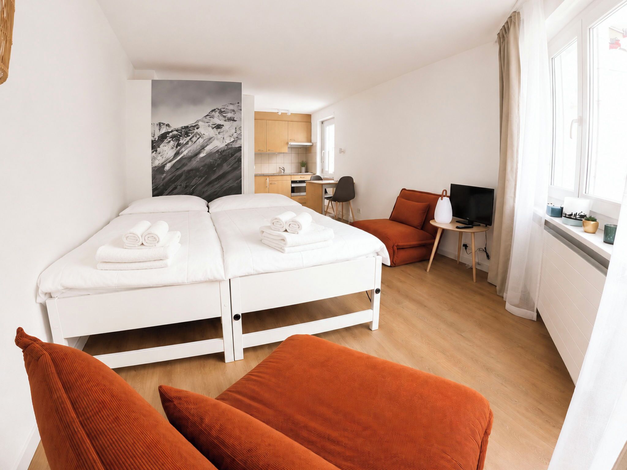 A hotel room with a bed, a desk, a chair, and a TV.