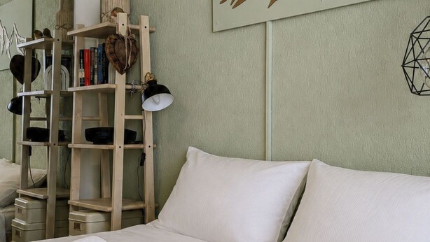 Ein Hotelzimmer mit einem Bett, Handtüchern, einem Bücherregal und einem Wandbild.