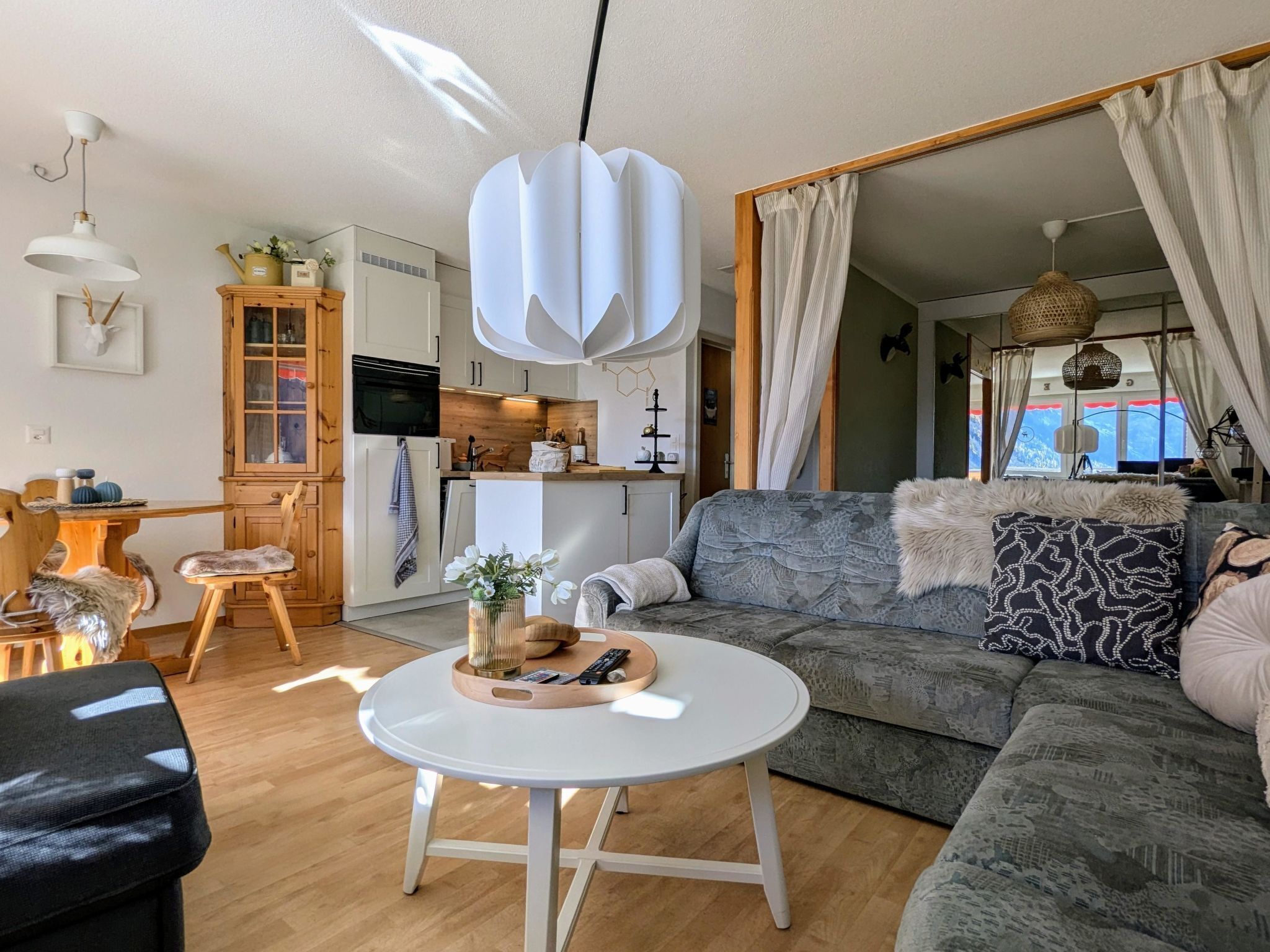 Una sala de estar moderna con un sofá, una mesa de centro y un comedor con un mueble de madera.