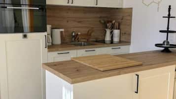 Uma cozinha moderna com armários brancos, bancada de madeira e prateleira suspensa preta.