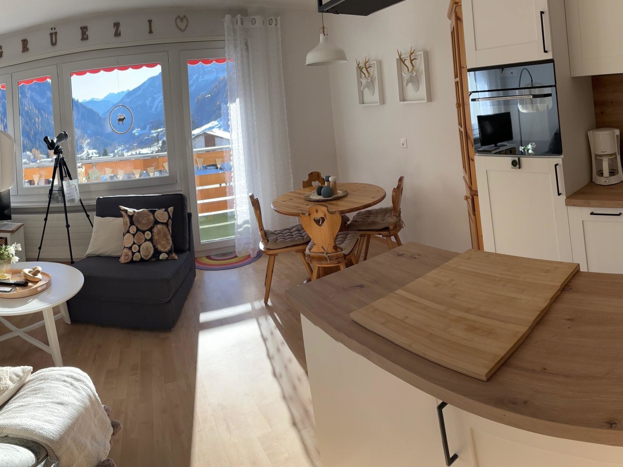 Una sala de estar acogedora con un sofá, una mesa de comedor y una zona de cocina con refrigerador y cafetera.