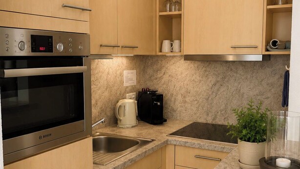 Una cucina compatta con forno Bosch, lavello, macchina del caffè e una pianta in vaso.