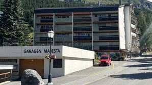 Un edificio con la scritta 'GARAGEN MAISTETA', un'area di parcheggio e un'auto rossa parcheggiata di fronte.