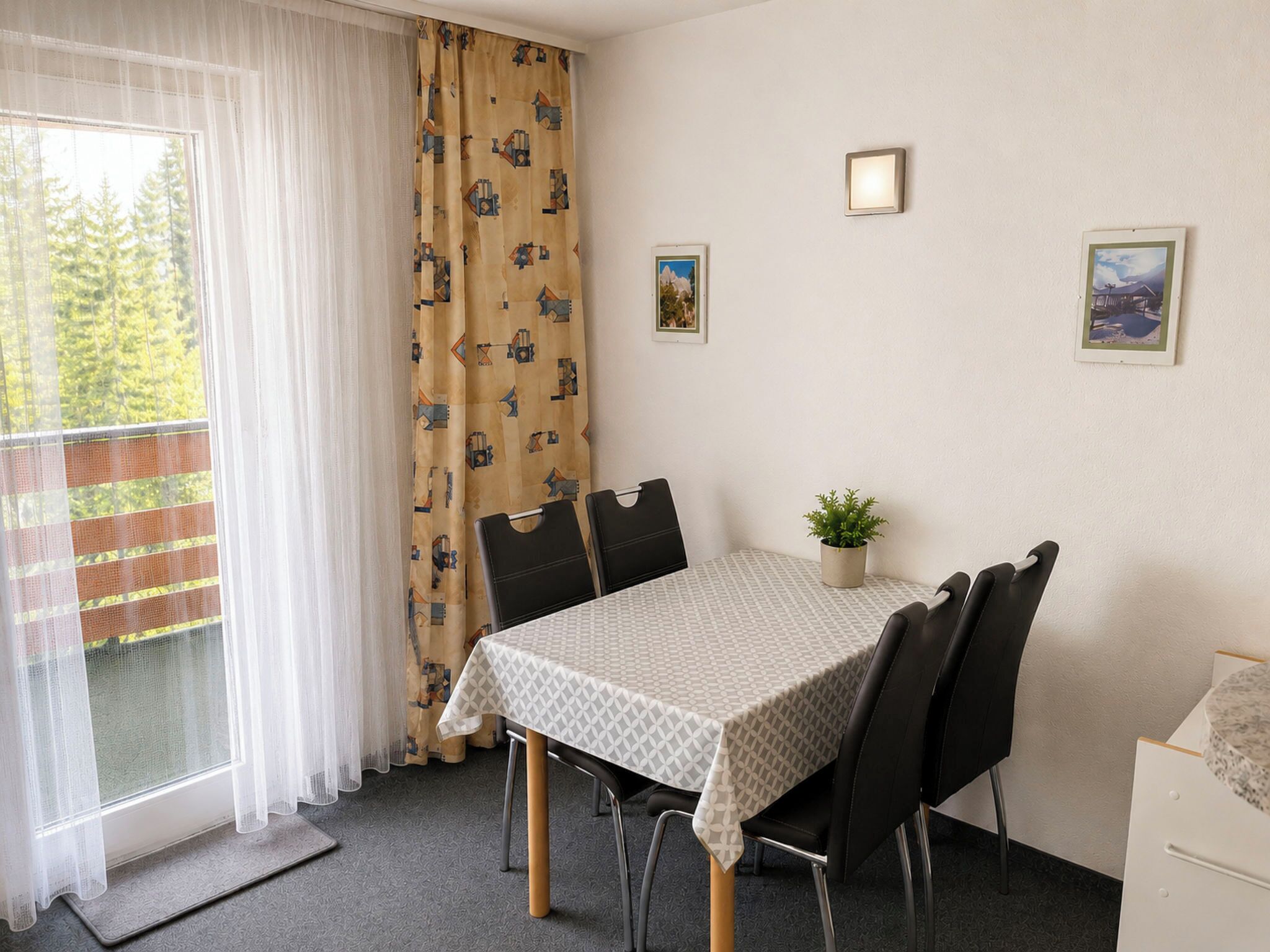 Comedor con una mesa dispuesta para cuatro, una planta en maceta y dos luces fijadas a la pared.