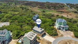 An aerial view of a coastal property with multiple buildings, including a large house with a balcony and a smaller structure with a pool. - HIAV13: The Green Turtle and the Nest (Avon)