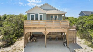A two-story beach house with a wooden deck, outdoor seating, and a view of the surrounding greenery. - HIAV13: The Green Turtle and the Nest (Avon)