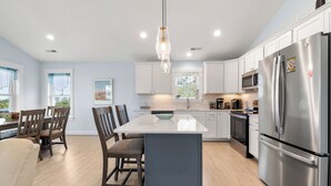 A modern kitchen with a central island, stainless steel appliances, and a hanging light fixture. - HIAV13: The Green Turtle and the Nest (Avon)