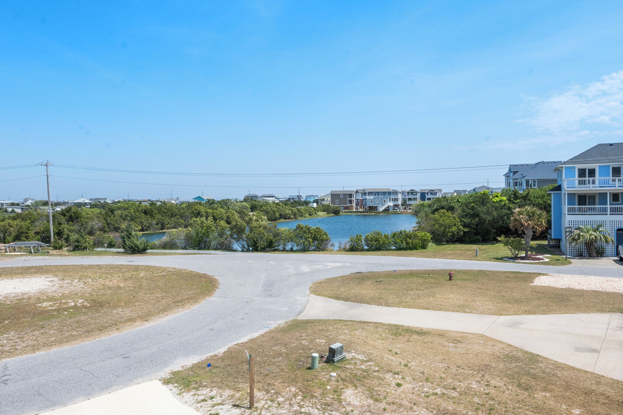 A residential area with a lake, houses, and a clear sky.