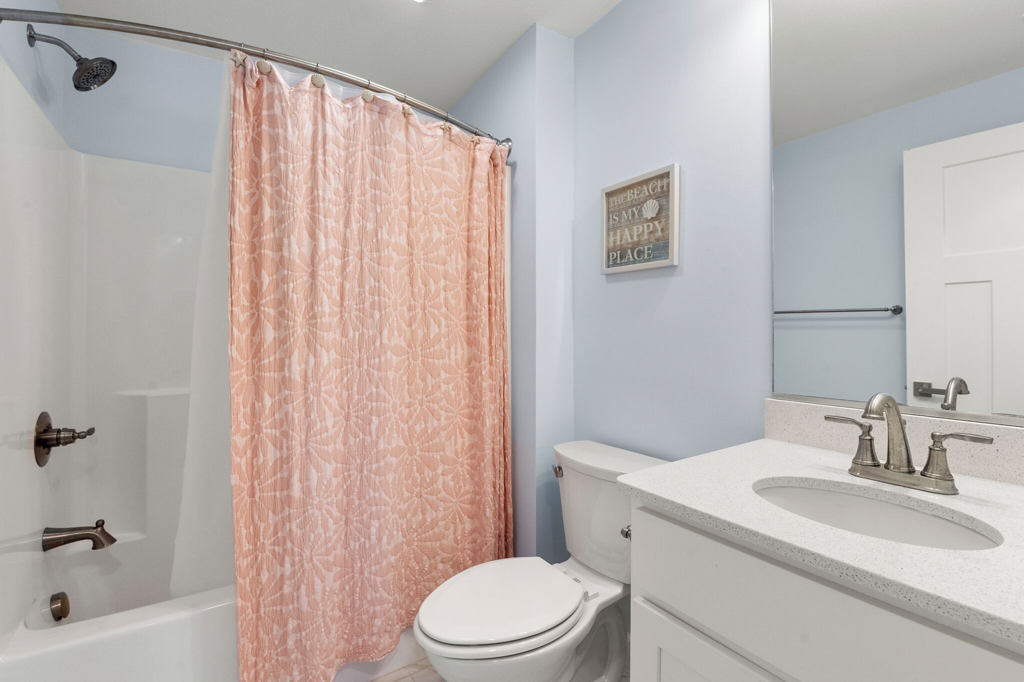 Un baño con ducha, inodoro, lavabo y un perchero para toallas.
