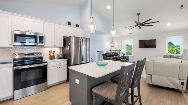 A modern kitchen with stainless steel appliances, a central island, and a dining area with a sofa and chairs. - HIAV13: The Green Turtle and the Nest (Avon)