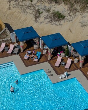 Un espace aménagé au bord de la piscine, avec des chaises longues, une piscine et une plage de sable.