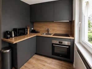 A compact kitchen with dark cabinets, a wooden countertop, a stainless steel sink, and a built-in oven. - Majesta Leukerbad # 3-bed apartment, Dusche, WC by Interhome (Leukerbad)