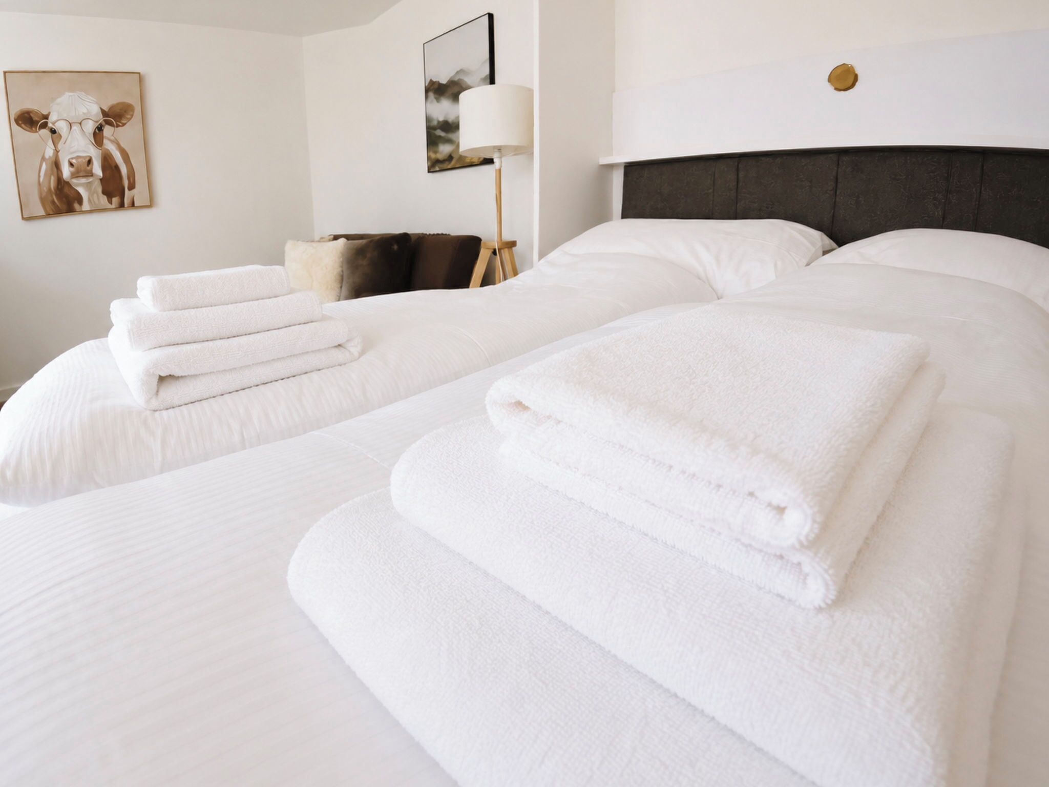 A hotel room with two beds, each with neatly folded white towels.