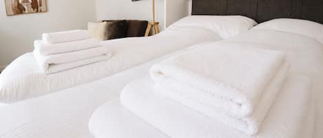 A hotel room with two beds, each with neatly folded white towels.