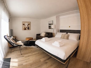 A hotel room with a bed, a chair, a sofa, a lamp, and artwork on the walls. - Majesta Leukerbad # 3-bed apartment, Dusche, WC by Interhome (Leukerbad)
