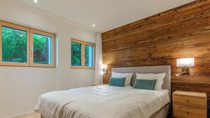 Ein Schlafzimmer mit einem Bett, zwei Nachttischen, einer Wand mit Holzvertäfelung und zwei Fenstern.
