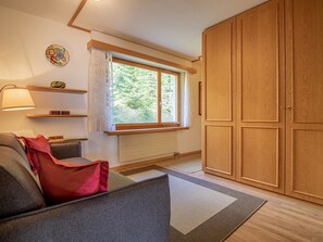 A room with a sofa, a window with curtains, a radiator, and a wardrobe. - I dr Rehwiesa C11 by Arosa Holiday Appartement/Fewo,   Rehwiesa 11 C by Interhome (Arosa)