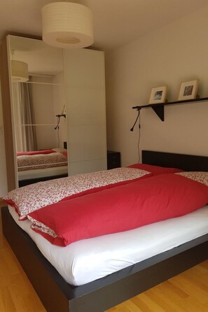 A bedroom with a bed, a large mirror, a shelf with pictures, and a hanging light fixture. - Edelweiss C 22 # 4-bed apartment, Dusche, WC 4-Bettwohnung, Dusche, WC by Interhome (Leukerbad)