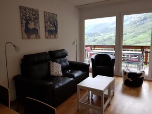 Ein Wohnzimmer mit einem schwarzen Ledersofa, einem weißen Couchtisch und zwei Hirschbildern an der Wand.