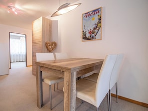 A dining area with a wooden table and white chairs, a heart-shaped decoration, and a poster on the wall. - Gentiana B-2 by Arosa Holiday Appartement/Fewo,   Gentiana B2 by Interhome (Arosa)