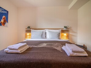 A hotel room with a bed, two bedside lamps, a poster on the wall, and towels on the bed. - Weisshorn-Apartment by Arosa Holiday Appartement/Fewo, Bad, WC, 6-Bettwohnung by Interhome (Arosa)