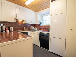 Une cuisine de taille réduite avec des meubles blancs, un four encastré et un lave-vaisselle.