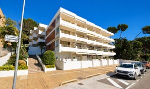 Ein mehrstöckiges Gebäude mit Balkonen und einer Treppe, mit einem Schild, das 'Carrer de la Cala Crances' ausweist.