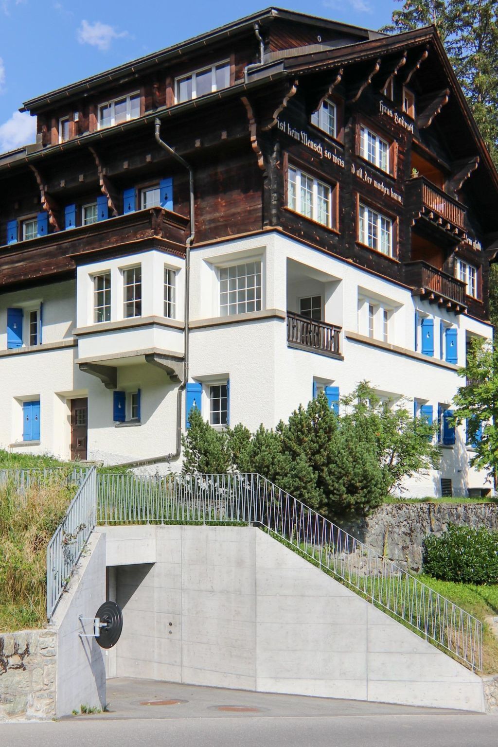 Un edifici de diversos pisos amb balcons, una escala i una paret de pedra.