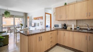Et moderne køkken med træskabe, en granitbordplade og et spiseområde med bord og stole.