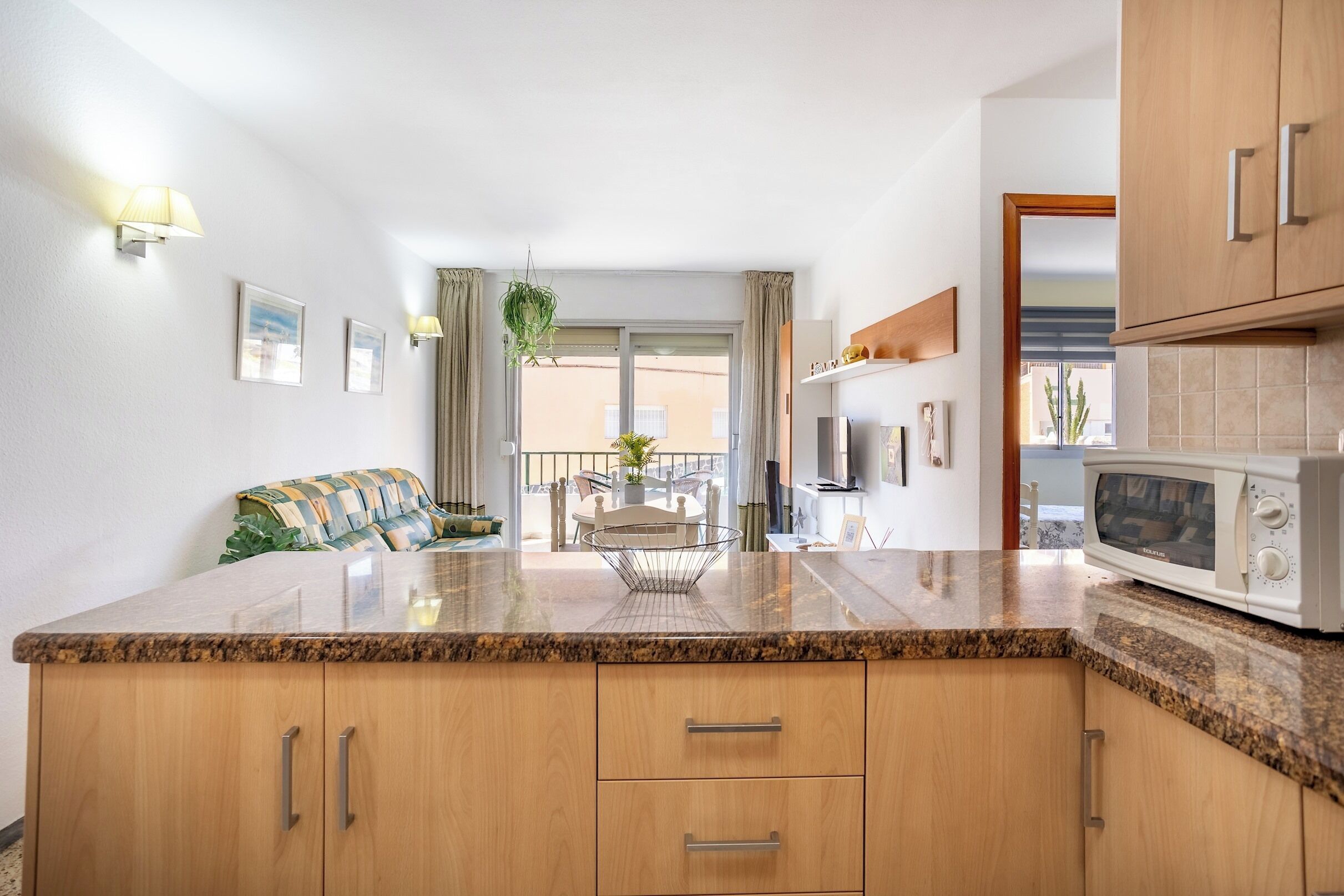 A kitchen with granite countertops, wooden cabinets, a microwave, and a dining area with a table and chairs.