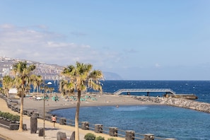 A coastal promenade with palm trees, a beach, and a rocky pier. - Home2Book Sunny Terrace Apt, el Rincón de ManFe (Candelaria)
