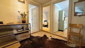 A room with a wooden floor, a cowhide rug, a bookshelf, a vase with flowers, and a mirror on the wall. - Pradella 2 by Arosa Holiday Studio, Dusche und Badewanne, 4-Bettwohnung by Interhome (Arosa)