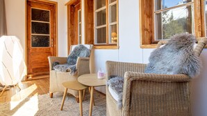 A cozy room with wicker furniture, wooden beams, and large windows. - Pradella 2 by Arosa Holiday Studio, Dusche und Badewanne, 4-Bettwohnung by Interhome (Arosa)