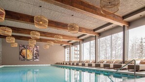 Ein Hallenbad mit Holzbalken und hängenden Korbschwingenlampen.
