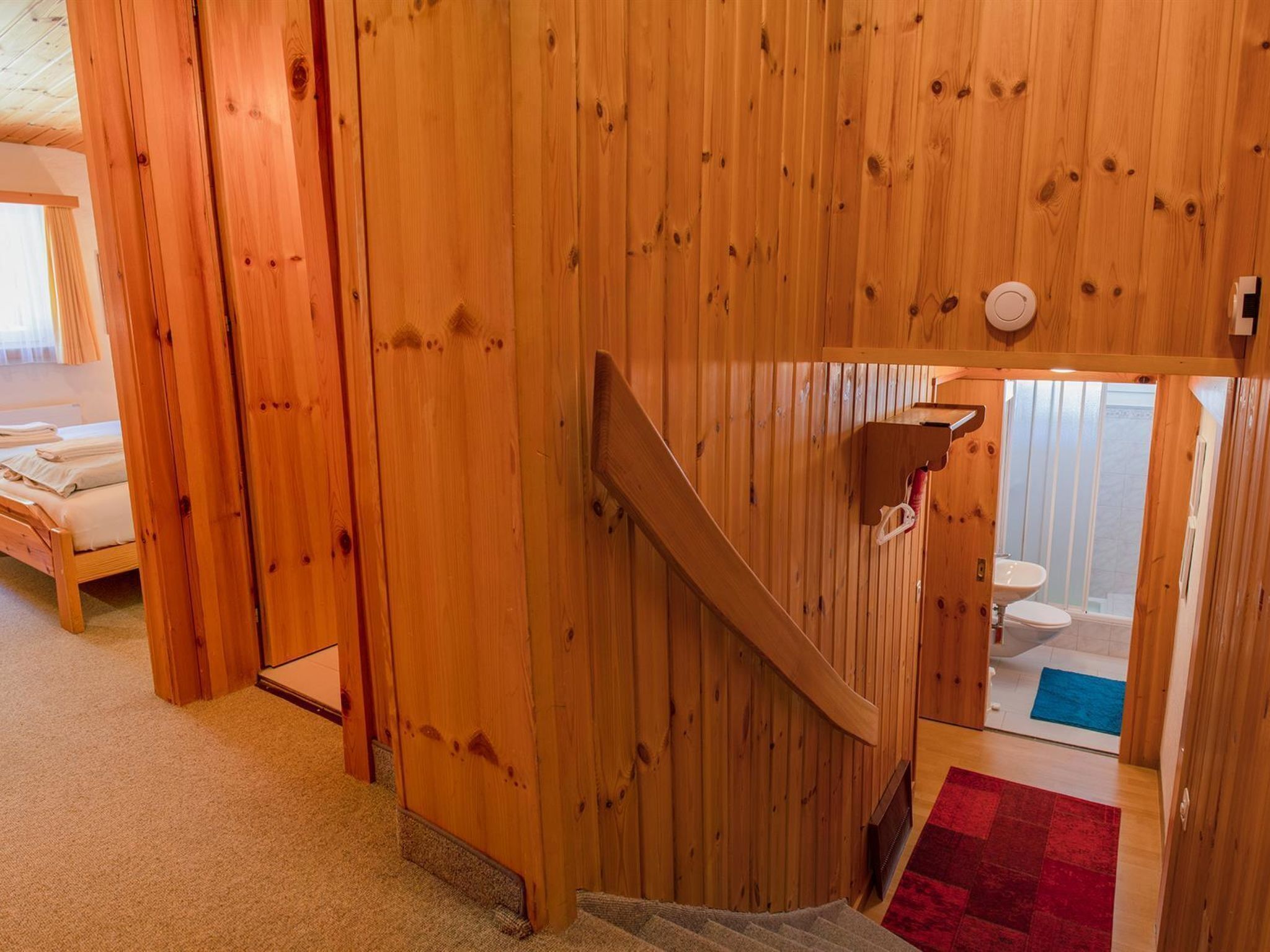 Een houten trap die leidt naar een badkamer met een wastafel en toilet.