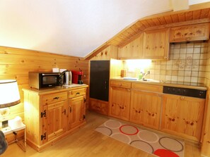 A compact kitchen with wooden cabinets, a microwave, a refrigerator, and a dishwasher. - Furkablick Yvonne by Arosa Holiday Appartement/Fewo, Bad, WC Furkablick Yvonnne by Interhome (Arosa)