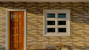 Una stanza con una porta in legno, una finestra a più vetri e un piccolo tavolo con una tovaglia a motivi geometrici.
