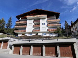 A multi-story building with balconies, a covered entrance, and a parking area. - Dschember by Arosa Holiday Appartement/Fewo, Bad, WC, 4-Bettwohnung by Interhome (Arosa)
