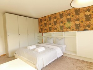 A bedroom with a bed, a wardrobe, and a patterned wall. - Dschember by Arosa Holiday Appartement/Fewo, Bad, WC, 4-Bettwohnung by Interhome (Arosa)