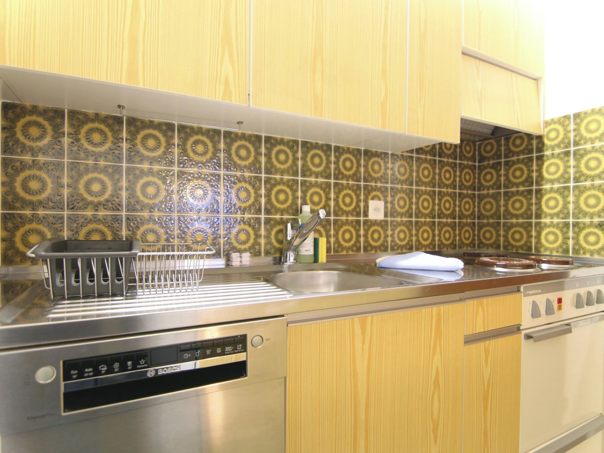 A kitchen with a Bosch dishwasher, a sink, and a stove.