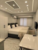 Una habitación de hotel con cama, escritorio, armario y televisor.