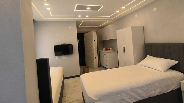 A modern hotel room with a bed, a TV, a wardrobe, and a bathroom. - Vizyon Konak (Burhaniye)