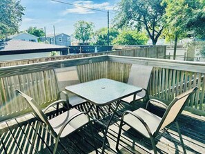 Eine Terrasse mit Tisch und vier Stühlen, umgeben von einem Holzzaun.